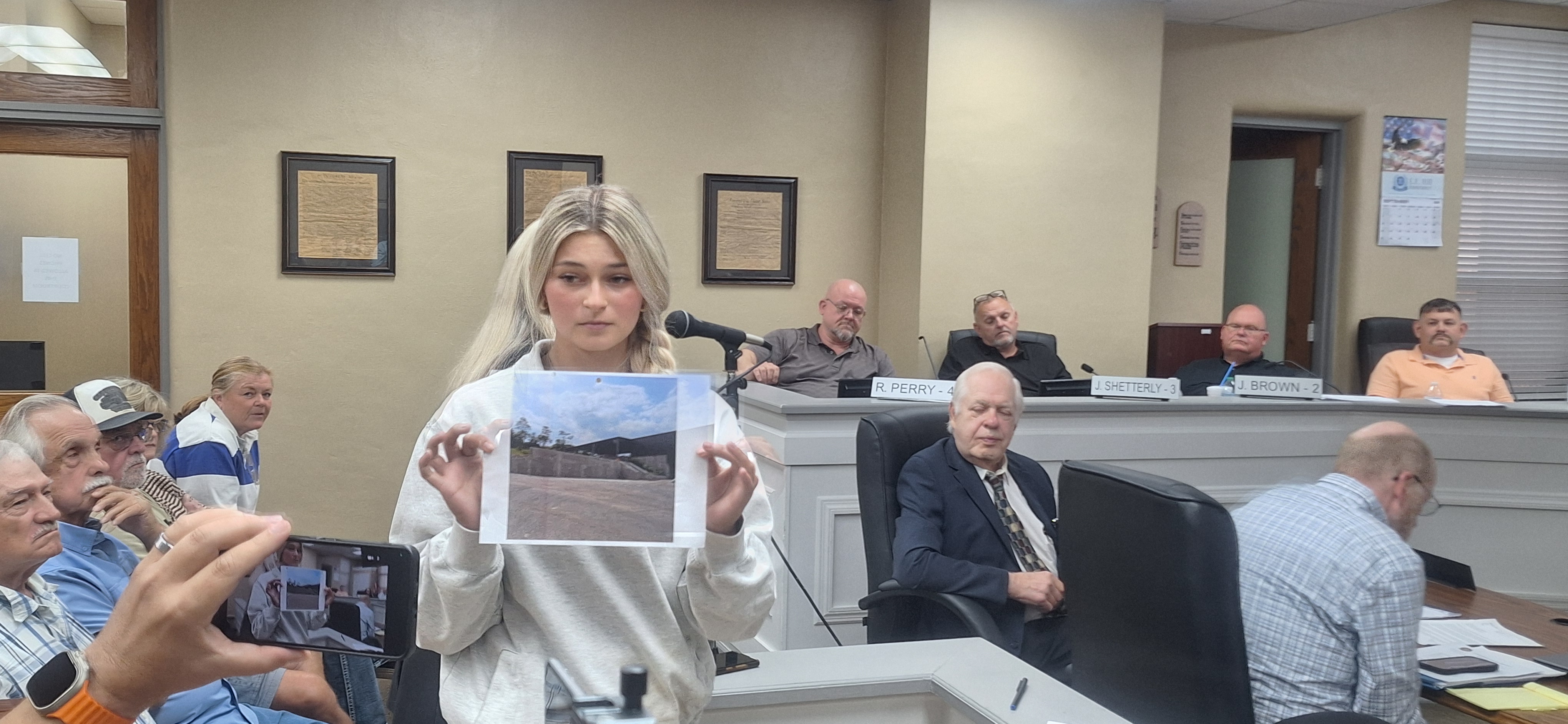 Commission G Shakira Goins holding up a photo of what the sanitation department looked like before David Adkins took over